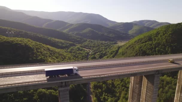 緑の丘に対して晴れた日にトラックの運転と高速道路の高架橋の空中ビュー — ストック動画