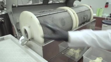 Siyah eldivenli bilim adamı CBD kapsüllerini alıyor ve kaliteyi kontrol ediyor.