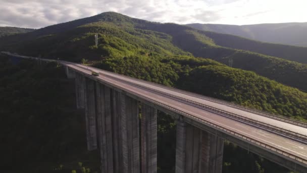 Az országúti viadukton haladó, zöld hegyekkel tarkított tehergépkocsi tetejére néző — Stock videók