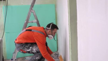 Close-up view of a craftsman hand applying and evening white plaster on a rough wall surface. Great for renovation tutorials, restoration, and professional repair projects.