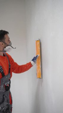 İnşaat işçisi, yenilenme sürecinde paten ve Spatula kullanarak duvardaki taze alçıyı düzleştiriyor. Yüksek kalite 4k görüntü