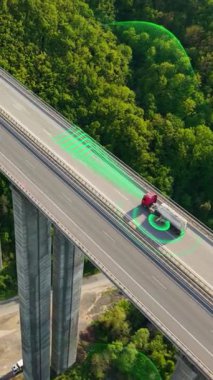 Aerial drone shot of a futuristic self-driving truck with a cargo trailer driving along a scenic viaduct road. Special effects show sensors scanning the surroundings and analyzing freeway traffic
