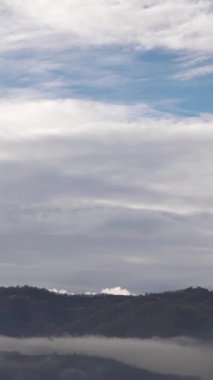 Hızlı hareket eden bulutlar, yüksek tepelerle çevrili bir vadi üzerinde sürükleniyor. Bu da değişimi ve dramatik havayı simgeliyor..