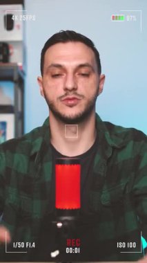 İçerik yaratıcısı, evde podcast sunarken, mikrofona konuşurken ve ilgi çekici anlar yaratırken kameranın önünde el hareketleriyle oyuncu karışıklığı gösterir..