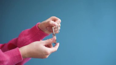 Kalp şeklindeki asma kilidi kilitleyen ellerin detaylı makro görüntüsü güvenli aşk duygusal güvenliği ve bağlılığı simgeliyor. Temiz stüdyo, romantik reklam ve ilişki için uygun hale getiriyor.