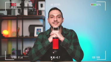 Genç bir adamın kendi stüdyosundan bir podcast 'i kaydetmesini izlemek profesyonel bir mikrofona açıkça konuşmak ve izleyicileriyle zahmetsizce iletişim kurmak..