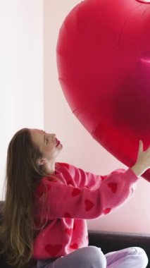 Sevgililer Günü 'nün tadını çıkaran mutlu bir kadın kalp süslemeleri ve süzülen kalplerle hayal gibi ağır çekimde..