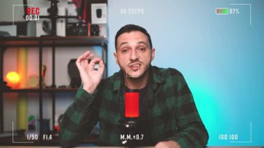 Genç adam bir ev podcast 'i sırasında görüşlerini paylaşıyor, bir stüdyo mikrofonuna güvenle konuşuyor, ilgi çekici ve profesyonel bir ses deneyimi yaratıyor..