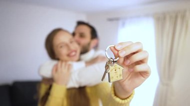 Gülümseyen çift yeni evine taşınmasını kutluyor. Kadın, elde ettiği başarıyı, yeni bir başlangıç ve ev sahipliği olarak görüyor..