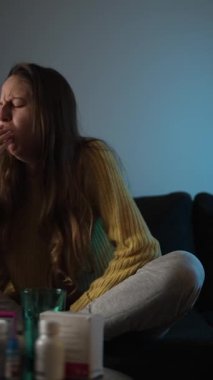 Kadın evde dinleniyor ve ateşi kontrol etmek için termometre kullanıyor. Grip belirtilerini ve ev sağlığı hizmetlerini gösteriyor..