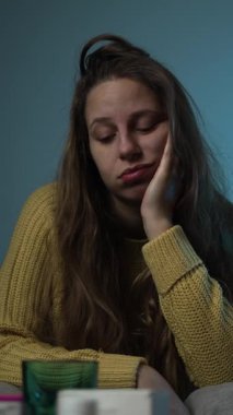 Kanepede dinlenen ve internette tıbbi destek arayan bir kadın günlük hastalık ve modern sağlık hizmetlerine erişimi gösteriyor..