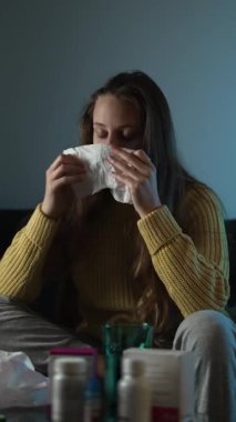 Kanepede oturup evdeki hastalık sırasında termometreyle ateşini ölçen hasta bir kadın..