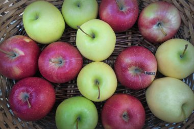 Kırmızı, yeşil ve sarı elmalar hasır bir sepet üst görünümde