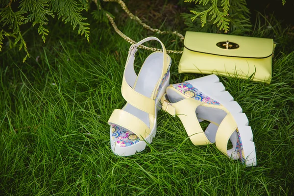 Yellow sandals and a handbag on the green grass — Stock Photo, Image