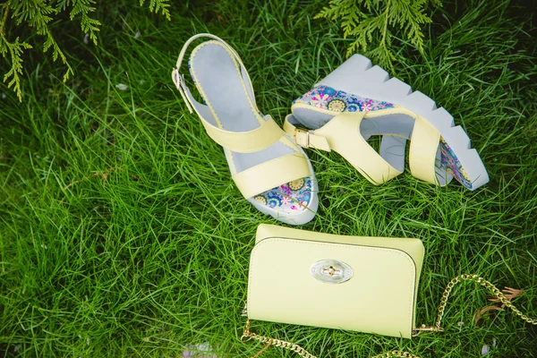 Yellow sandals and a handbag on the green grass — Stock Photo, Image