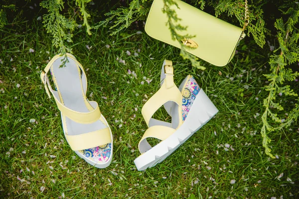 Sandalias amarillas y un bolso en la hierba verde — Foto de Stock