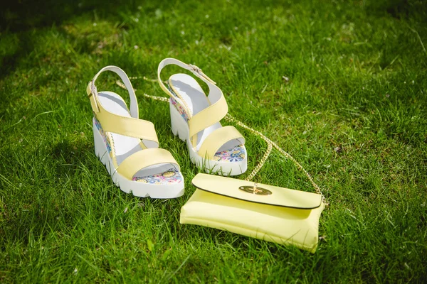 Yellow sandals and a handbag on the green grass — Stock Photo, Image