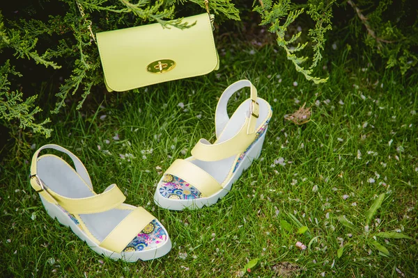 Sarı sandal ve yeşil çimenlerin üzerinde bir el çantası — Stok fotoğraf