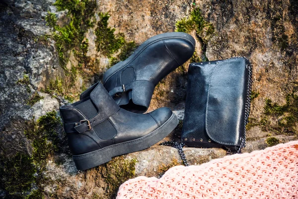 Black leather boots and black handbag on granite and moss, female soda — Stock Photo, Image