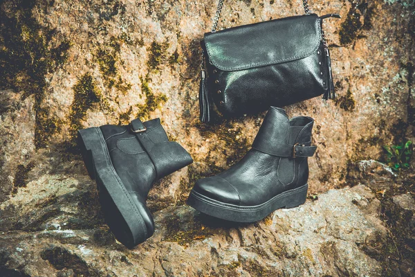 Zwarte leren laarzen en zwarte handtas op graniet en moss, vrouwelijke soda — Stockfoto