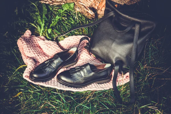 Botas de cuero negro y bolso de mano negro en granito y musgo, soda femenina — Foto de Stock