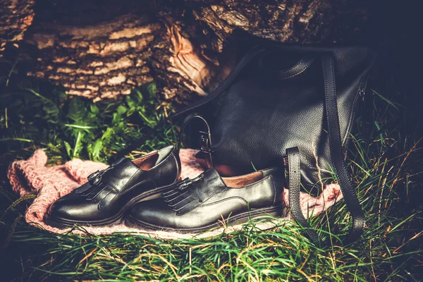 Botas de cuero negro y bolso de mano negro en granito y musgo, soda femenina — Foto de Stock