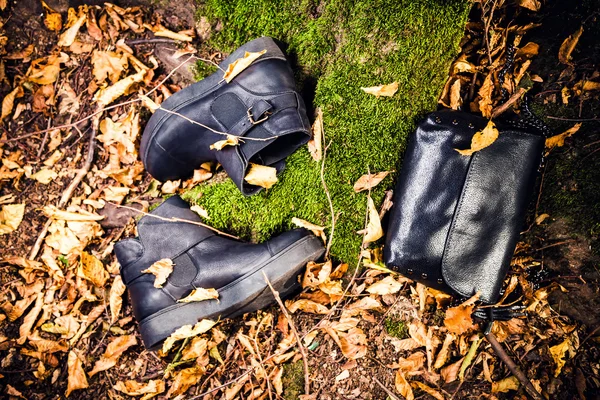 Botas de cuero negro y bolso de mano negro sobre musgo, soda femenina — Foto de Stock