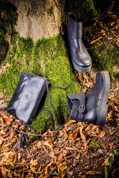 Botas de cuero negro y bolso de mano negro sobre musgo, soda femenina — Foto de Stock