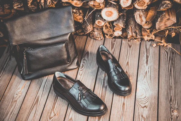Черная кожаная обувь и рюкзак на деревянном фоне, женская обувь — стоковое фото