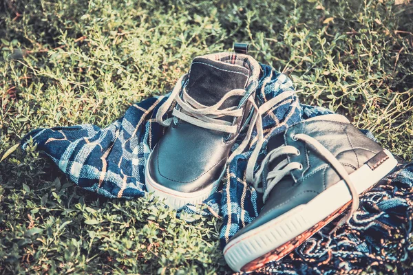 Men's shoes on the grass wrapped in a scarf — Stock Photo, Image