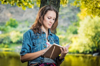 öğrenci üniversite Nehri yakınında bir parkta bir defter seyir