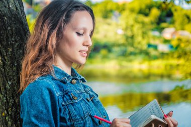 öğrenci üniversite Nehri yakınında bir parkta bir defter seyir