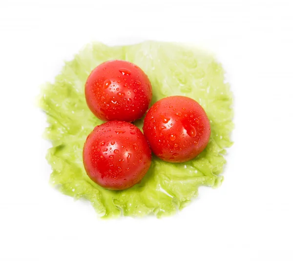 Three tomatoes lying on a sheet of green salad — Stock Photo, Image