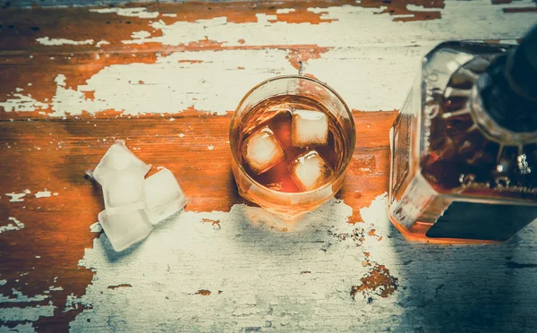 Whiskey with ice cubes, vintage photo, a bottle of whiskey — Stock Photo, Image