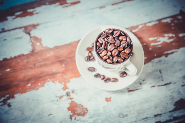 Grains de café dans une tasse sur un fond en bois — Photo