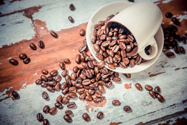 Szétszórt szemes kávé egy csésze, egy fából készült háttér — Stock Fotó