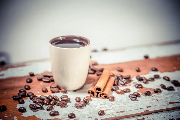 Grains éparpillés de café dans une tasse sur un fond en bois — Photo