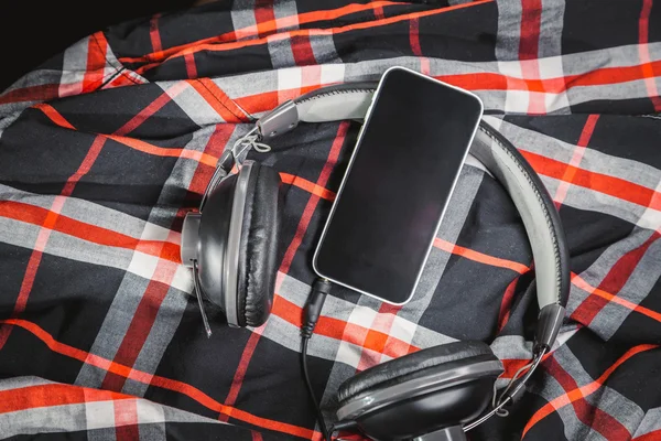 Telefono e cuffie su una camicia, ascoltando musica — Foto Stock