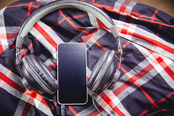 Телефон и наушники на рубашке, слушая музыку — стоковое фото