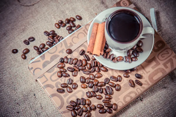 Chicchi sparsi di caffè in una tazza su uno sfondo di legno — Foto Stock