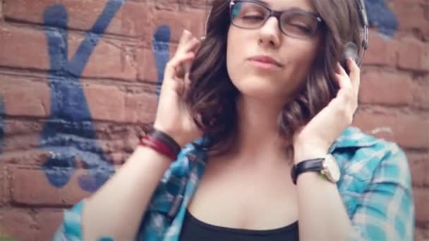 Красивая девушка слушает музыку на стерео наушниках — стоковое видео