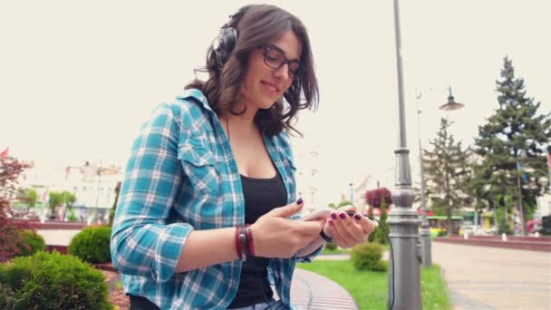 Flicka lyssnar på musik i parken — Stockvideo