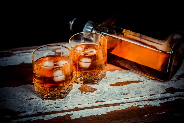 Two glasses of whiskey vintage photo, a bottle on the bar — Stock Photo, Image