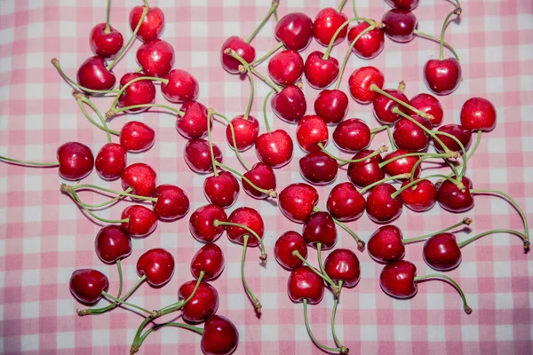 Background from cherries on a pink tablecloth — Zdjęcie stockowe