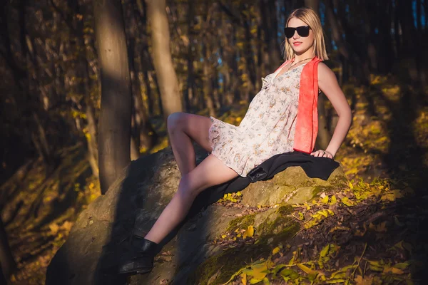 La chica en la bufanda roja y un vestido yace en una piedra — Foto de Stock