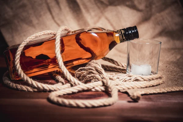 Whisky glas met ijs, een fles whisky en een touw — Stockfoto