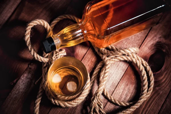 Bicchiere di whisky con ghiaccio, una bottiglia di whisky single malt — Foto Stock