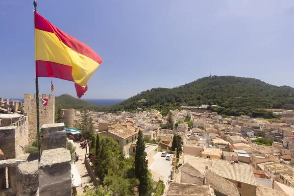Hiszpańską flagę pływające powyżej miasteczka Capdepera na Majorce — Zdjęcie stockowe