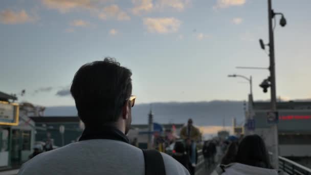 Santa Monica Pier pessoas azuladas no fundo, homens andando em câmera de câmera de câmera lenta para a frente tempo épico por do sol — Vídeo de Stock
