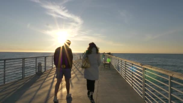 Pareja en Hermosa Beach Pier famosa escenaria La La Land, disfrutando de una hermosa vista del océano con destellos de sol — Vídeos de Stock